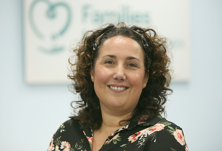 Michelle, a Family Support Adviser, is sat in front of our poster